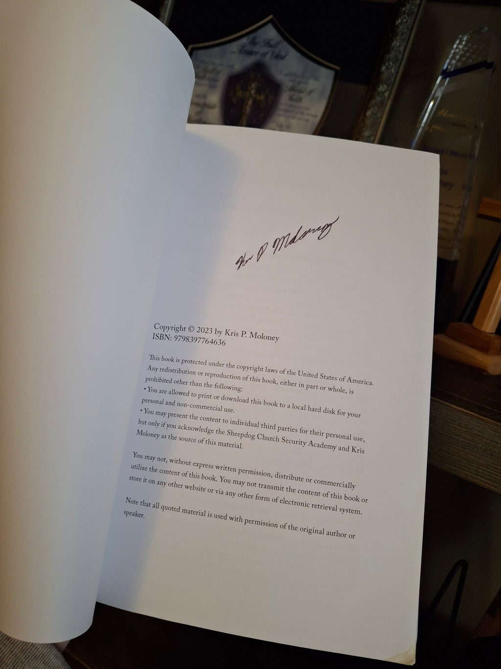 Inside page of Defending the Flock paperback showing Kris Moloney’s author signature on a signed copy
