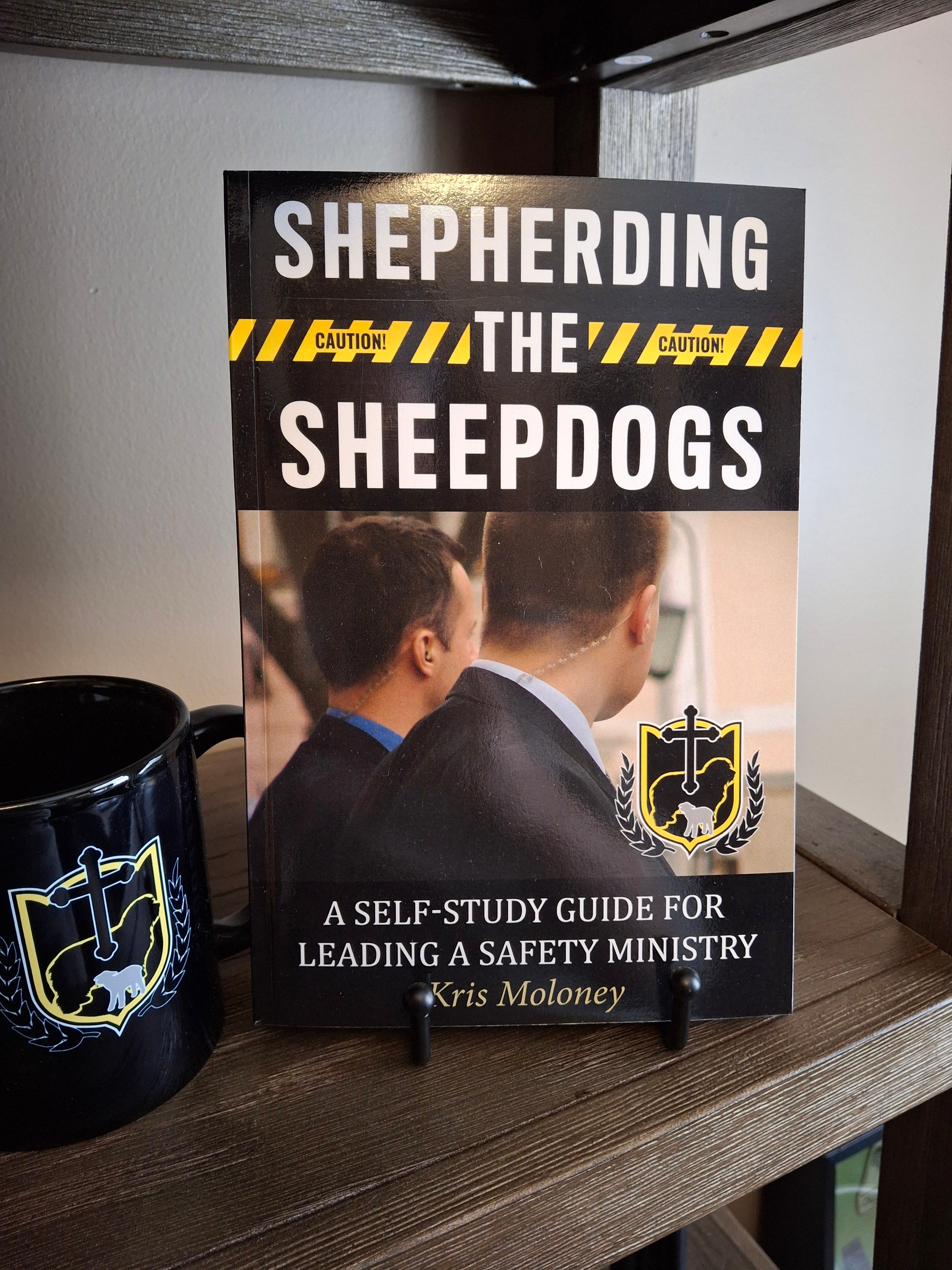 Shepherding the Sheepdogs paperback self-study guide for leading a church safety ministry displayed on a shelf next to an SCSA logo mug