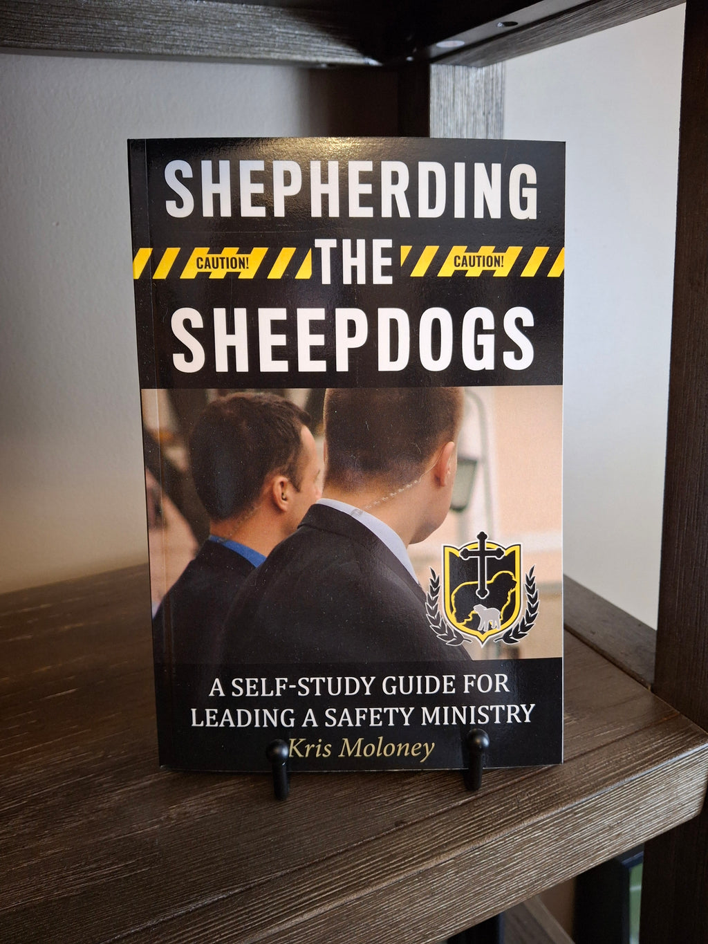 Shepherding the Sheepdogs paperback self-study guide for leading a church safety ministry displayed on a shelf